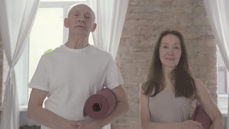 old male and female with a yoga mat looking at camera