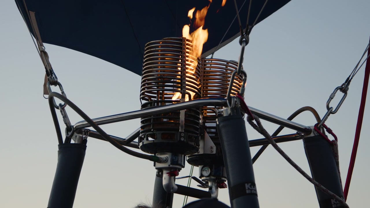 Un primo piano cattura il bruciatore della mongolfiera in azione, con fiamme vivaci che ardono intensamente, mostrando il potente processo di accensione essenziale per il volo.