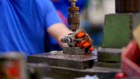 a person drills a hole with a drill on a metal element