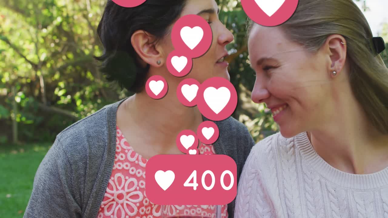 animación de emojis de corazón y números sobre una feliz pareja de mujeres caucásicas enamoradas