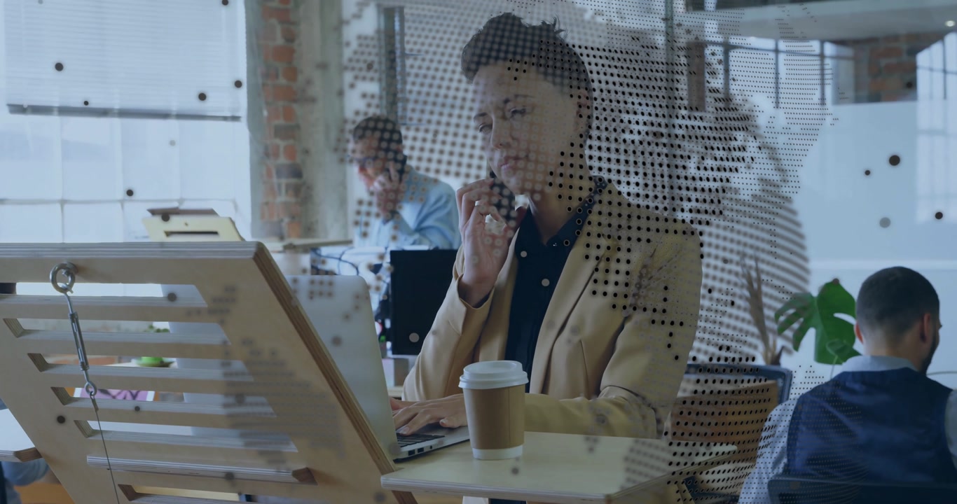 Woman talking on smartphone and typing on laptop in office, showing animated business charts