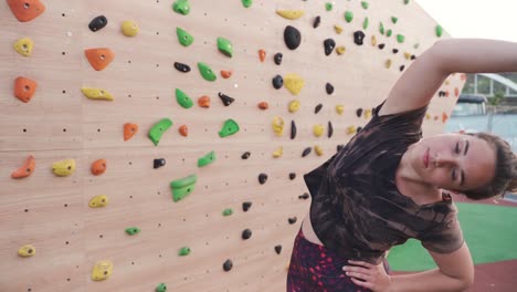 Frau-Dehnt-Sich,-Bevor-Sie-Eine-Boulderwand-Draußen-Vor-Der-Wand-Hochklettert,-Filmisch,-Nahaufnahme