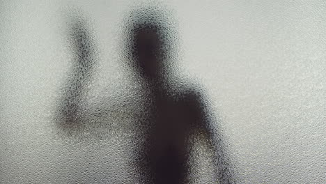 a female silhouette behind the frosted window dances slowly