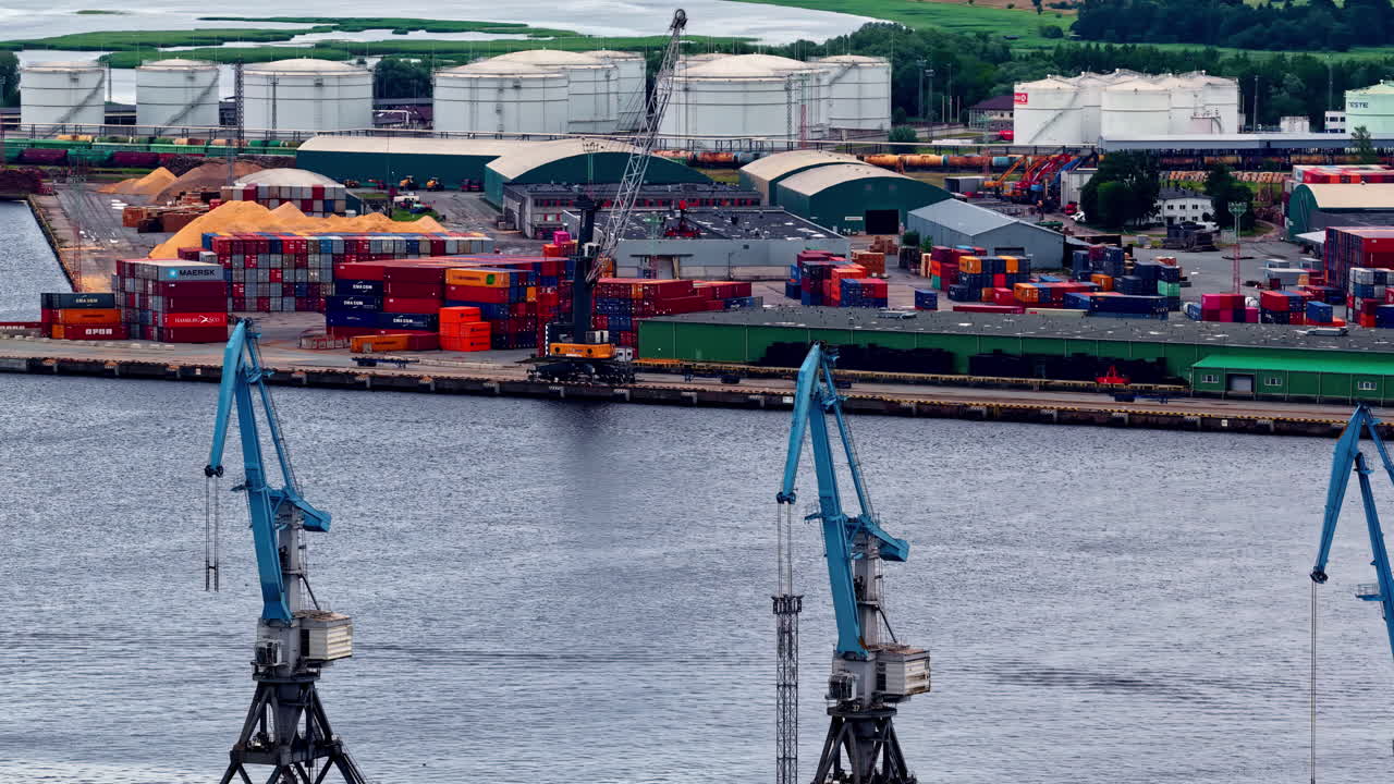 Colorful containers, cranes, and bulk materials near large fuel storage tanks at Riga’s port. Riga, Latvia