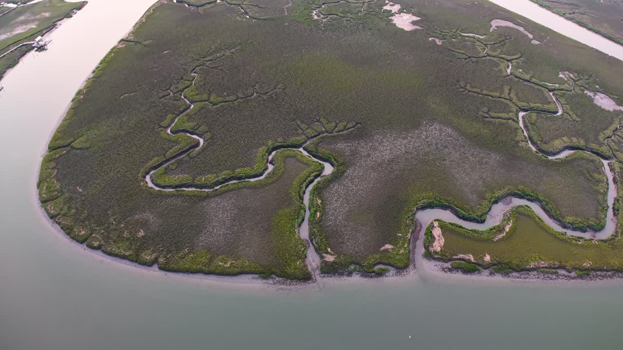 Aerial view of a small island with twisting tidal creeks surrounded by coastal marshland at sunset