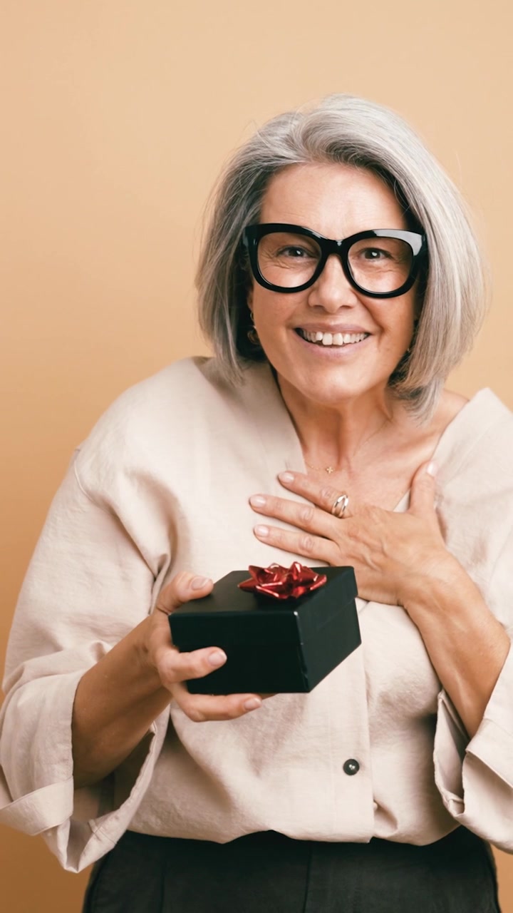 Donna matura entusiasta che tiene una scatola regalo