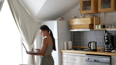 mujer trabajando en una computadora portátil en la cocina