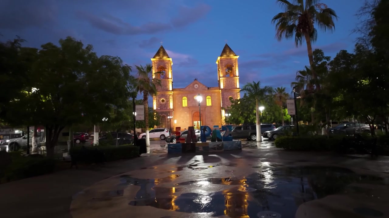 Uno scatto serale suggestivo che mostra la facciata illuminata della Cattedrale di Nostra Signora della Pace e la vivace insegna della città locale