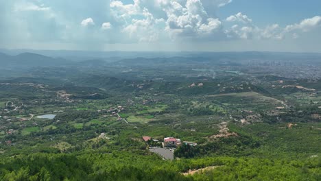 Tiro-De-Drone-De-Aldea-Rural-Con-Cielo-Nublado-Con-Ciudad-En-La-Distancia