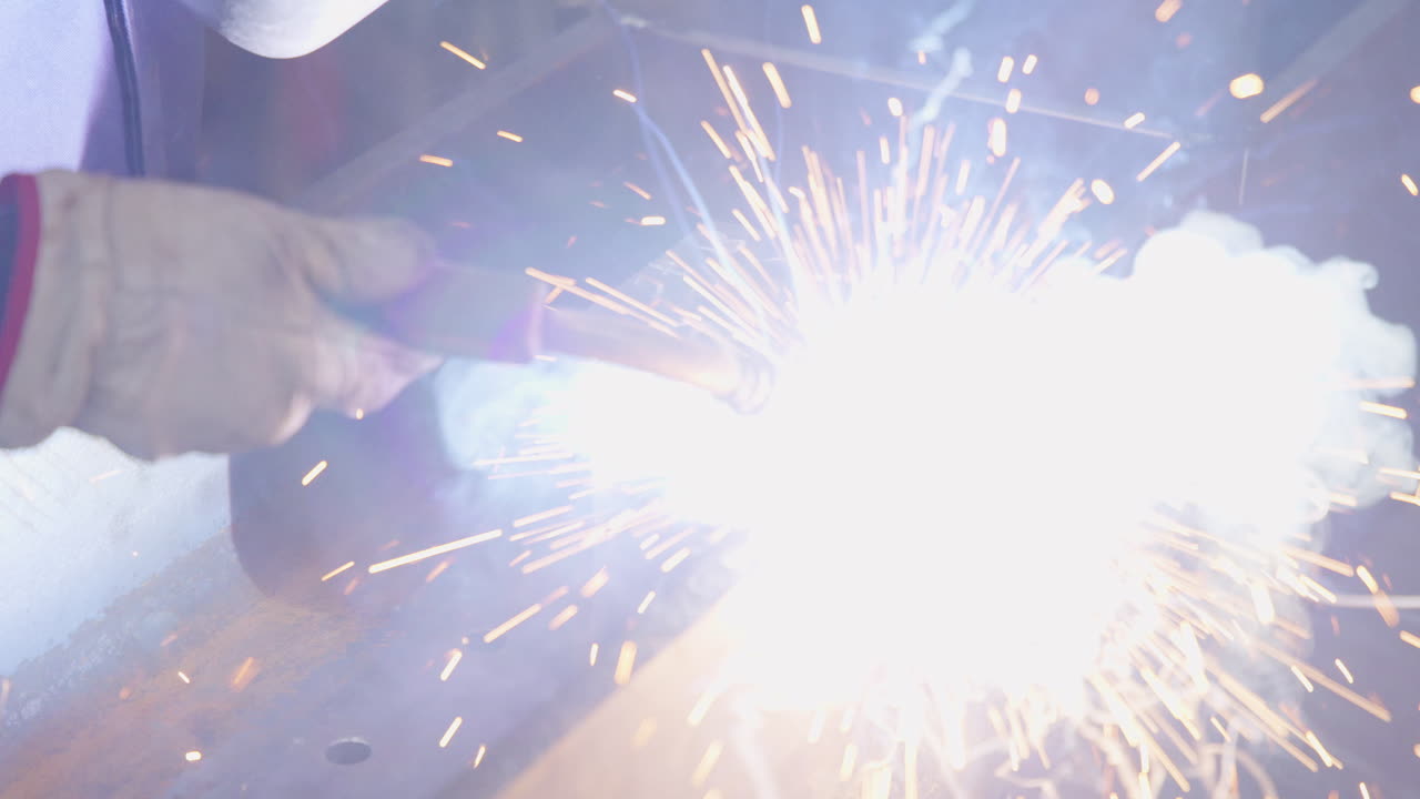 man welds plate to metal beam close shot slow motion