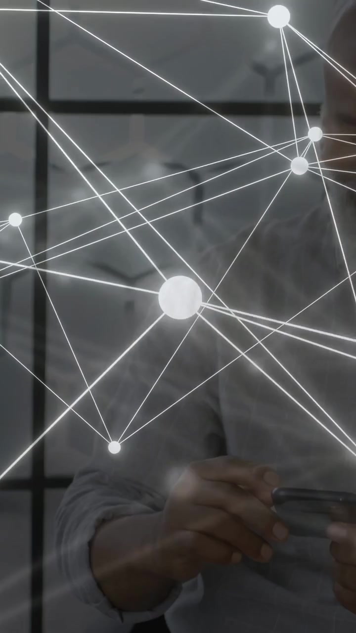 Video verticale: Uomo seduto in un ambiente tecnologico che usa il telefono e controlla un grafico, con un'interfaccia grafica che attraversa il busto.