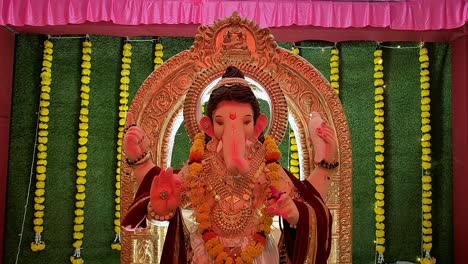 view of lord ganesha statues in ganesh pandal, illuminated by vibrant red light during festive celebrations in india.