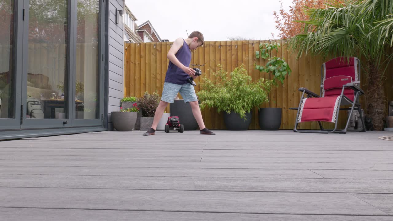 Young boy at home outdoors in the garden playing with his RC Car, Truck, 4 x 4
