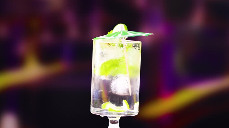 A mojito cocktail with lime and mint, set against a colorful blurred background, highlighting its refreshing appeal