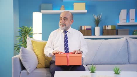 positive and cheerful old man waiting excited at home with gift box.