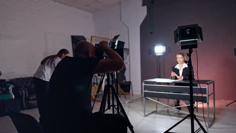 bald bearded photographer filming a lady sitting at desk. program, podcast or blog content footage.