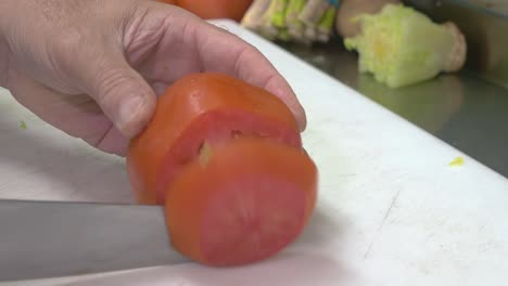 up close shot of chef hands cutting a tomatoe