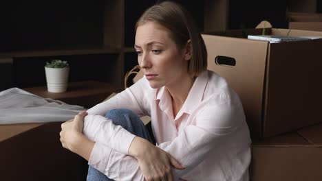 unhappy exhausted woman sit on floor near boxes with stuff