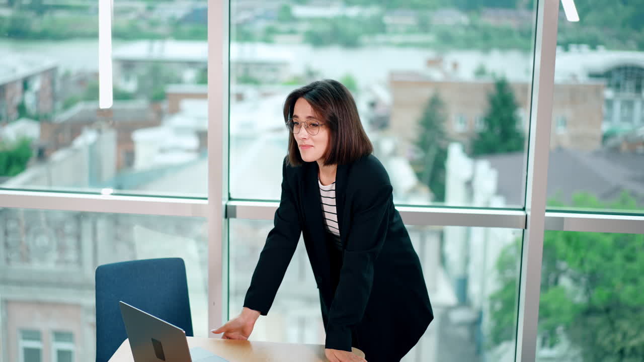 Young woman with short dark hair looks at her laptop and rejoices. Happy lady gets excited from information at computer.