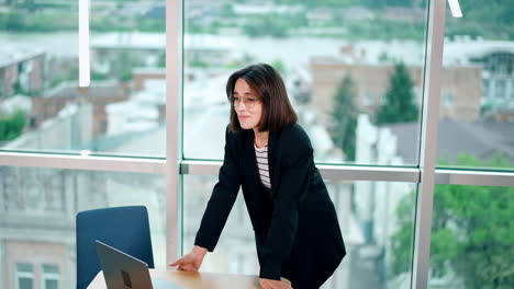 young woman with short dark hair looks at her laptop and rejoices. happy lady gets excited from information at computer.