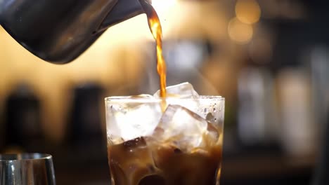 refreshing beverage preparation: pouring chilled drink over ice in a professional bar setting to make a perfect iced drink