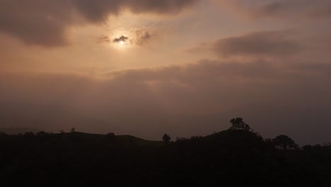 a truck shot along forested mountains under a foggy sky with sunshine hidden behind clouds.
