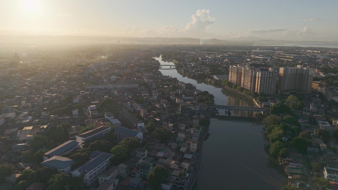 Riprese con drone che si muovono all'indietro sopra il fiume Pasig con la luce brillante dell'alba, quartieri residenziali e viste dello skyline a Metro Manila