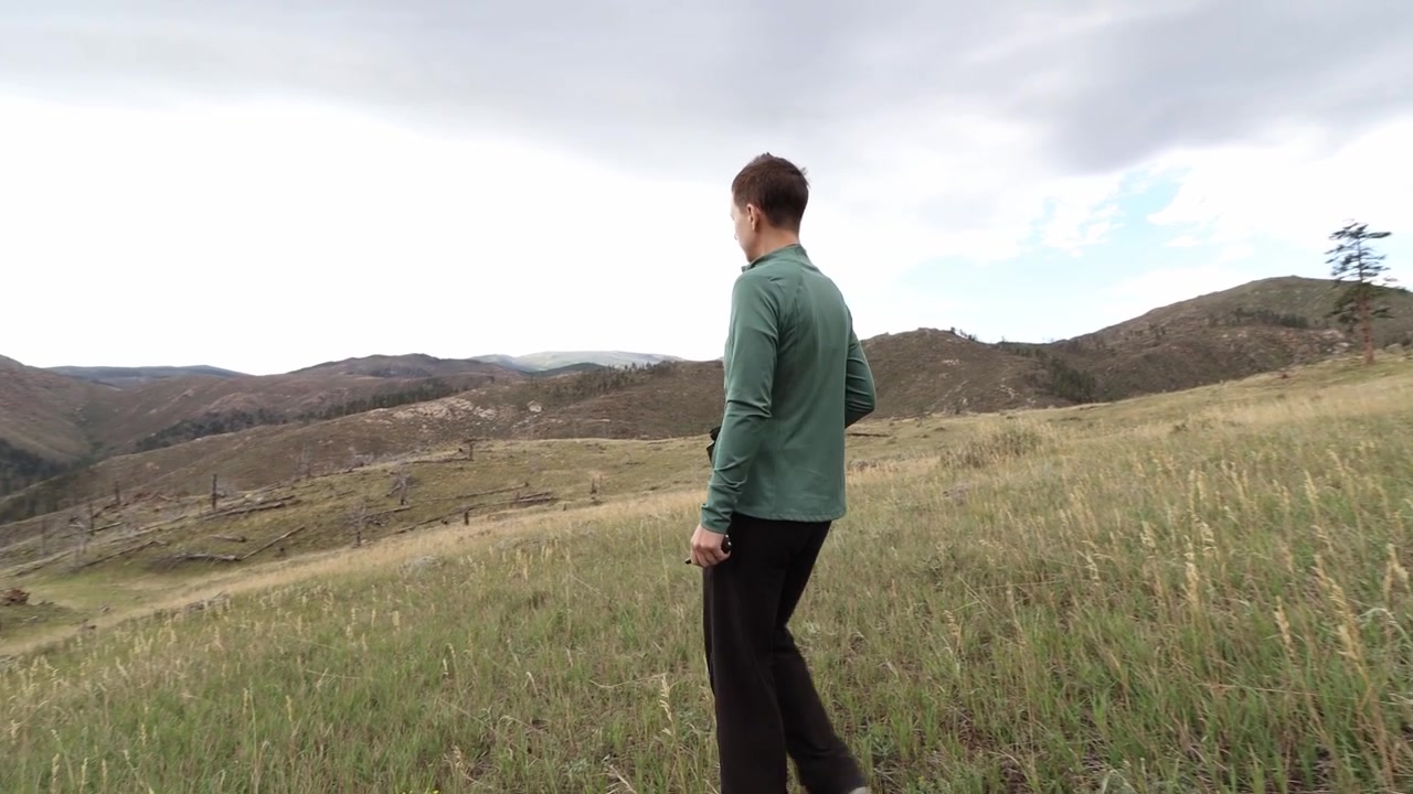 A backpacker explores the rugged terrain of the Rocky Mountains, hiking along a scenic trail surrounded by majestic alpine peaks and wilderness. Binoculars.