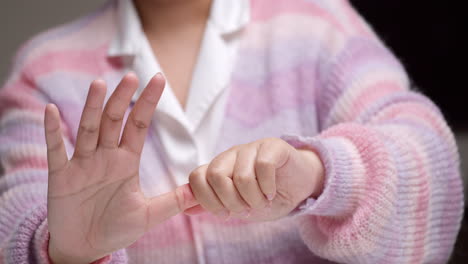 Woman-performing-self-massage-on-finger-joints-due-to-extensive-use-of-mobile-devices