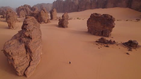 aerial view of man walking in desert landscape in tassili n'ajjer national park, algeria - drone shot