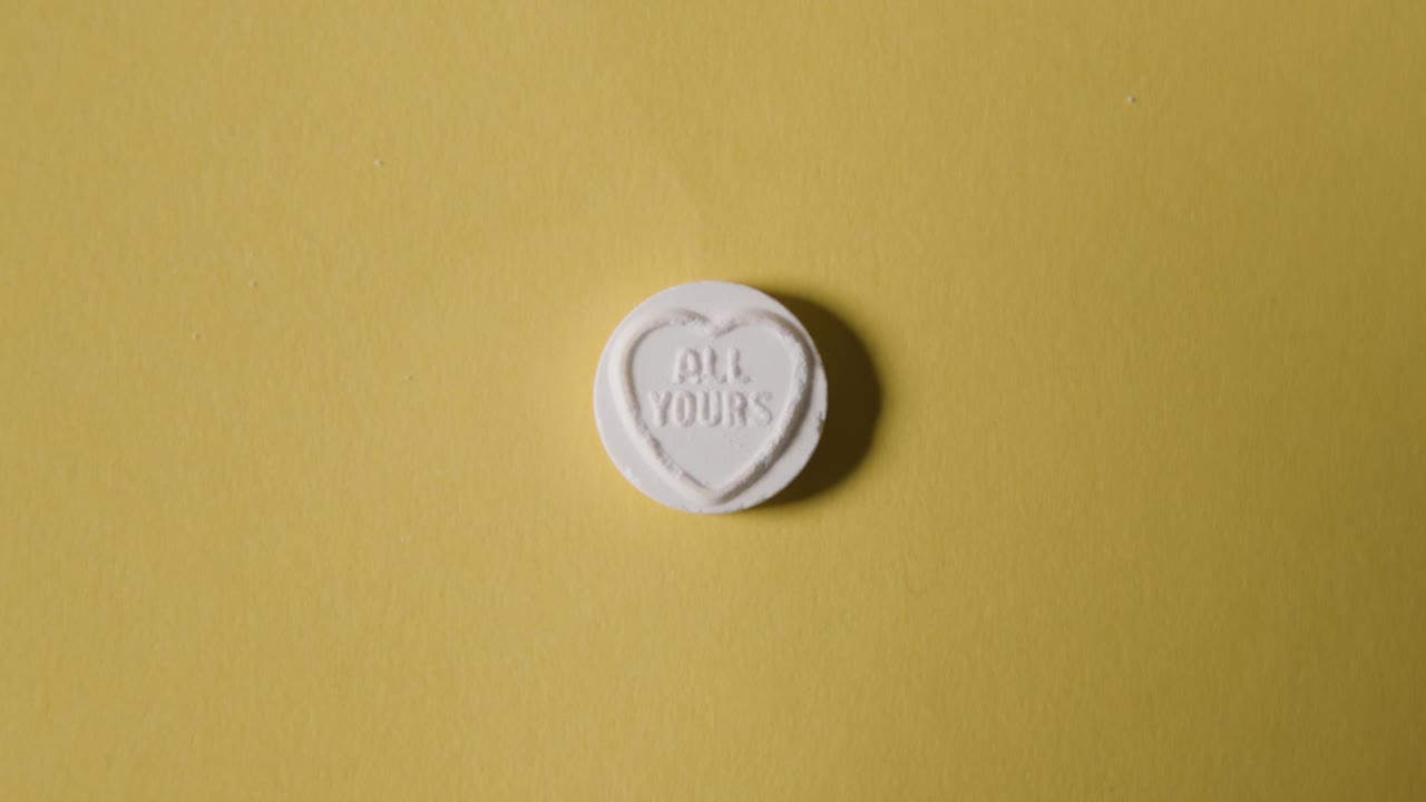 Hand Picking Up Heart Candy With All Yours Message On Yellow Background