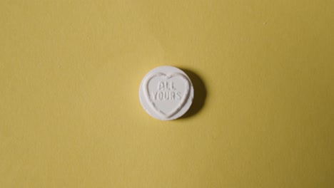 노란색 배경에 당신의 모든 메시지와 함께 심장 사탕을 손에 들고