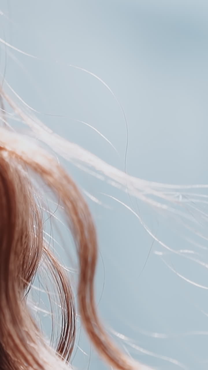 Woman with curly red hair locks waved by light wind at bright sunlight closeup slow motion. Pretty lady with elegant hairstyle. Beauty and fashion