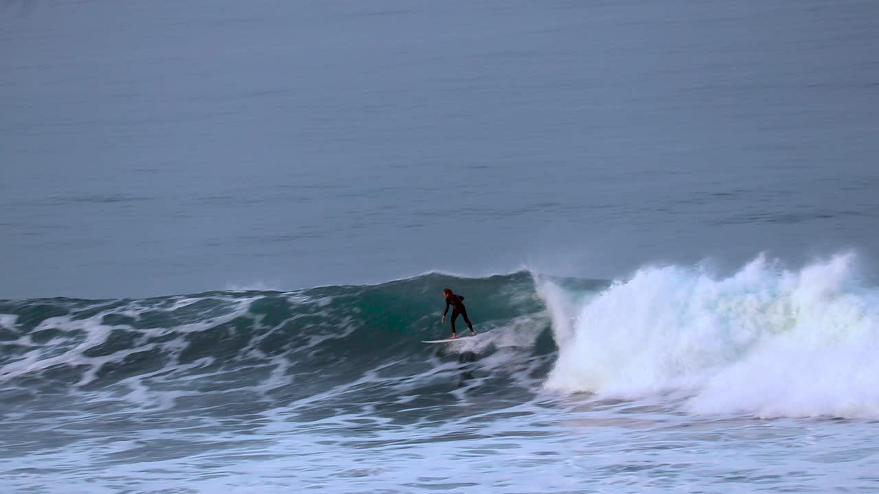 알아볼 수 없는 서퍼가 캘리포니아 칼즈배드에서 큰 파도를 잡았습니다.