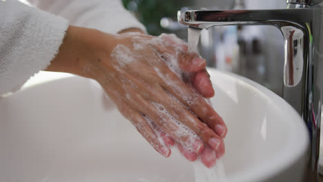 Mid-section-of-mixed-race-woman-washing-her-hands-in-bathroom