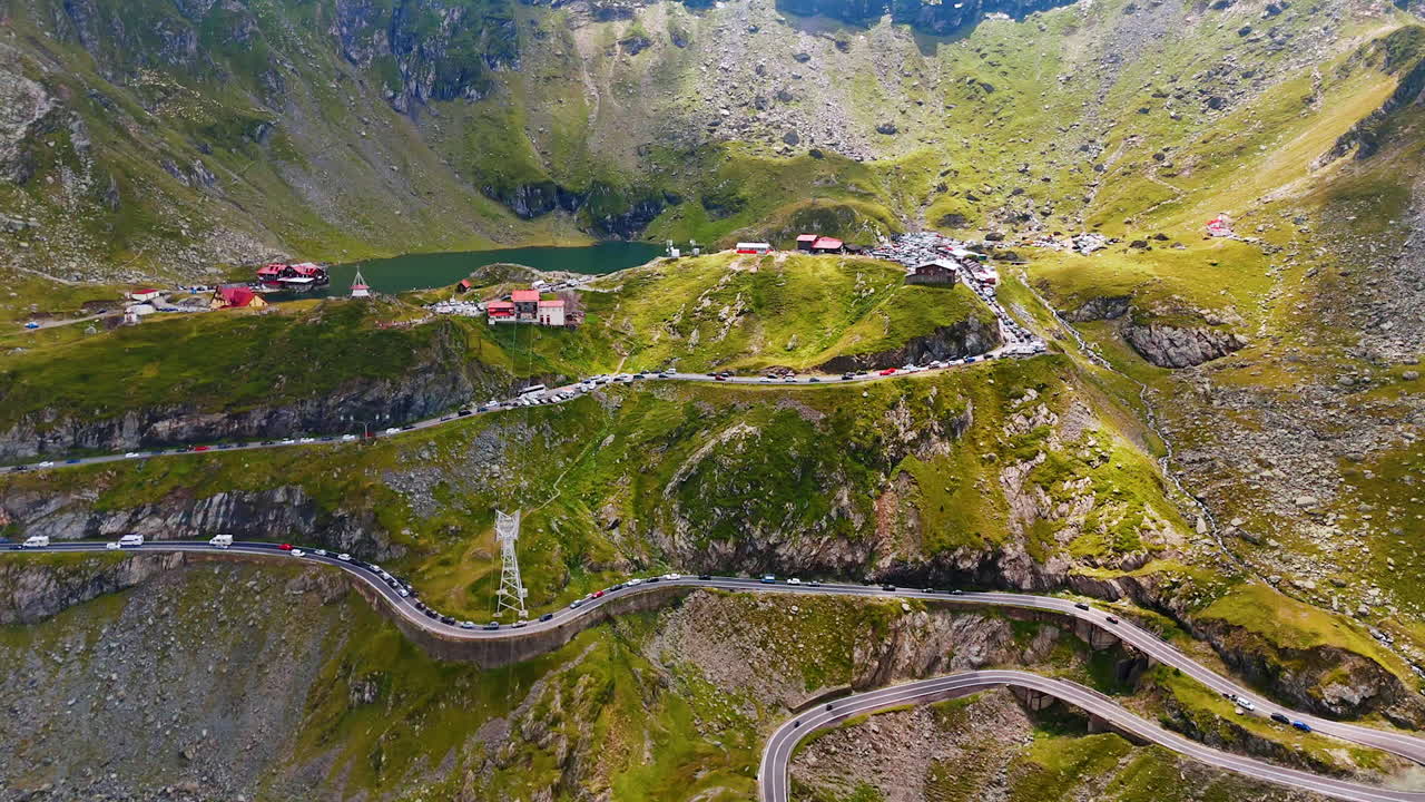 Mountain valley with Transfagarasan serpentine road in Romania. The iconic Transfagarasan road runs across a green valley in the Carpathians