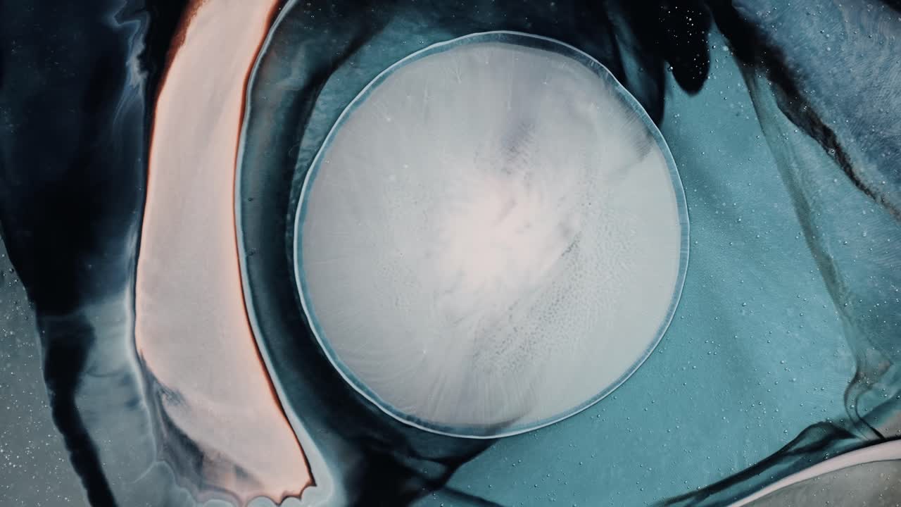 Blue colored ink liquid forming a multicolored nebula