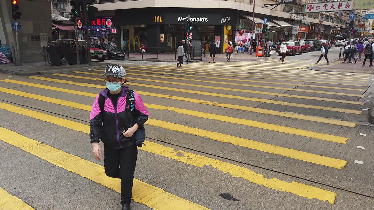 Corona Pandemic, People crossing the street in Downtown Hong Kong wearing protective face masks during Corona Virus outbreak.