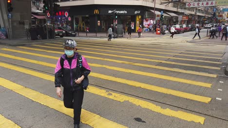 corona pandemic, people crossing the street in downtown hong kong wearing protective face masks during corona virus outbreak.