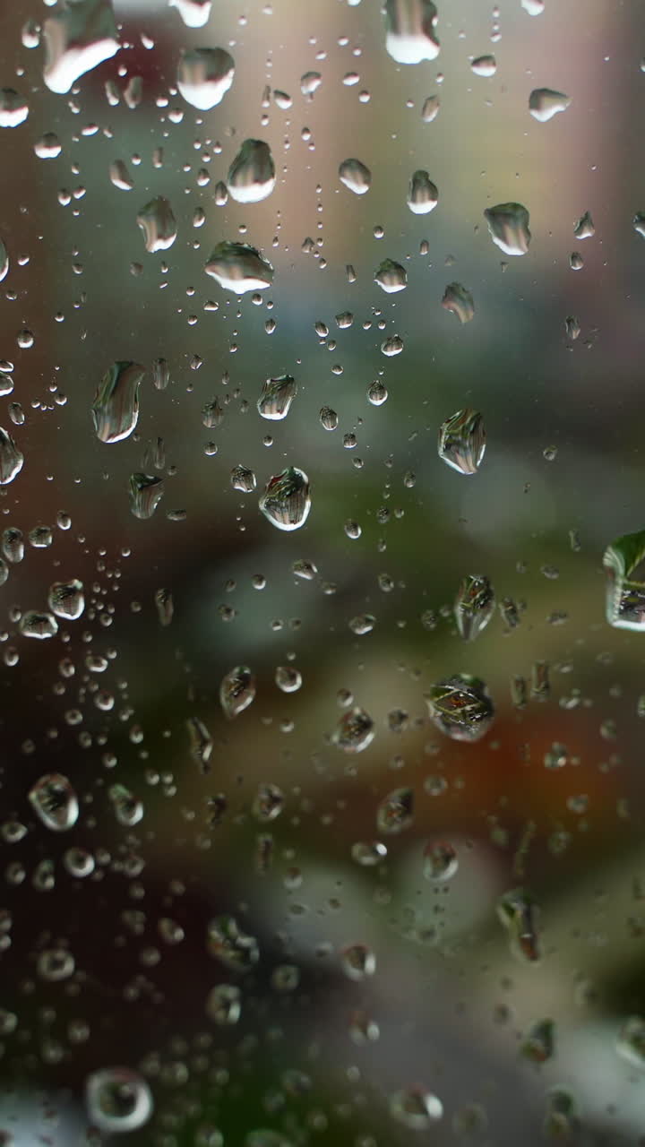 Window glass with large water drops. Rain drops on blur city background. Rainy season. Close-up. Vertical video
