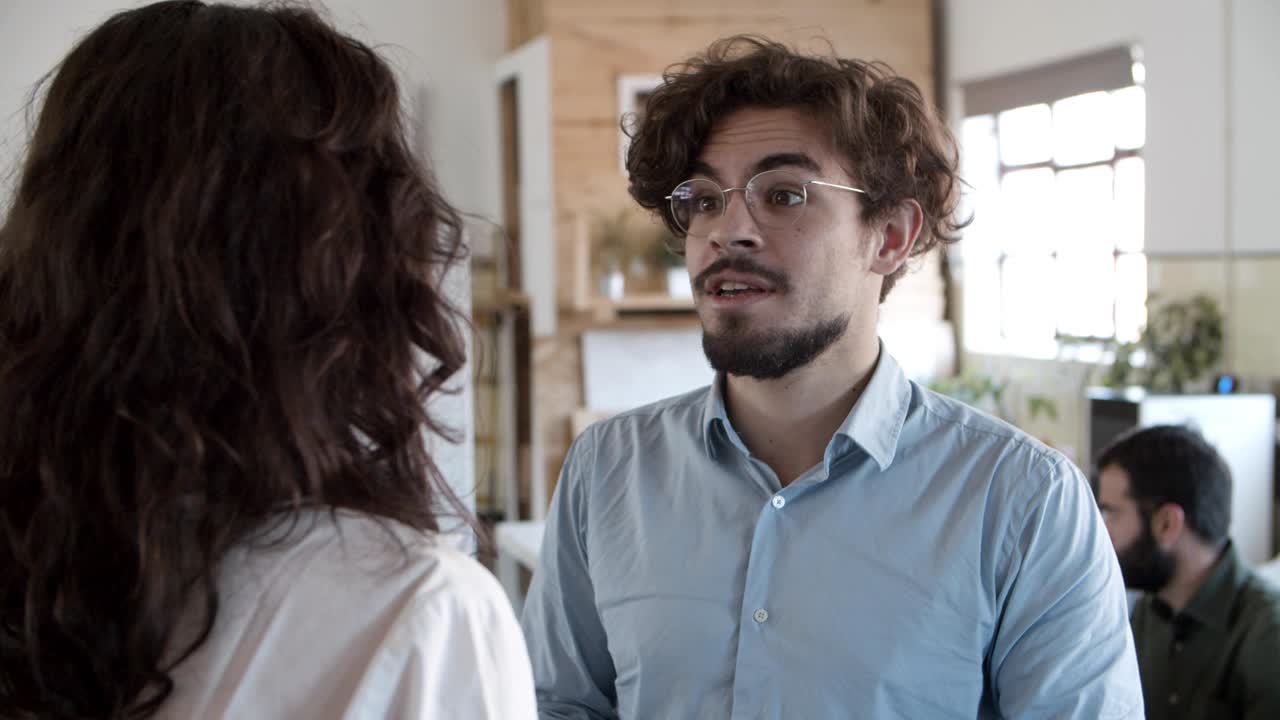 hombre barbudo sonriente con gafas hablando con una mujer joven