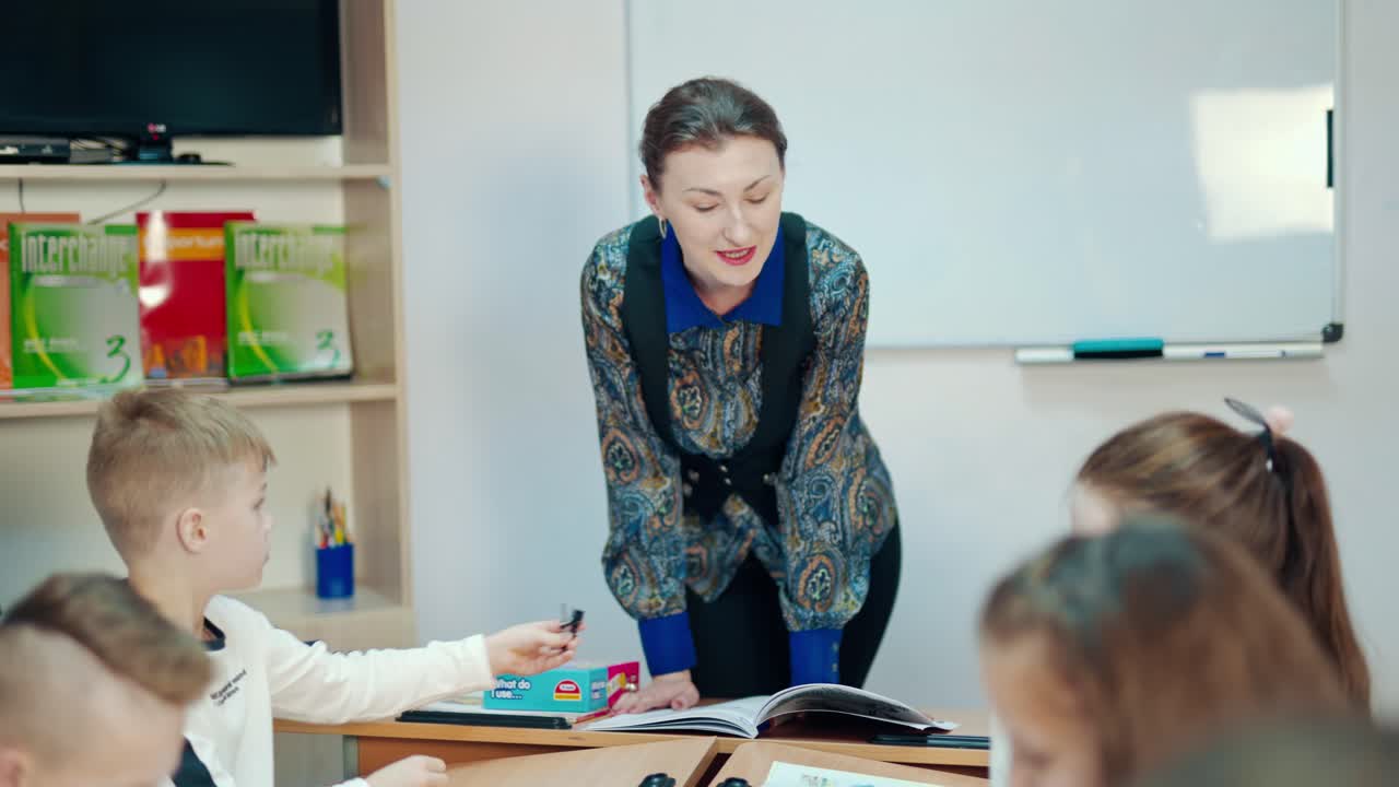 Young teacher learns small students. Beautiful pedagogue teaching primary school children in the classroom. Elementary education concept.