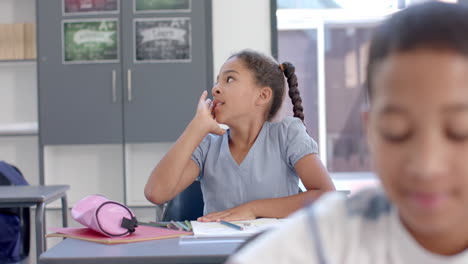 biracial girl ponders a question at school in a classroom