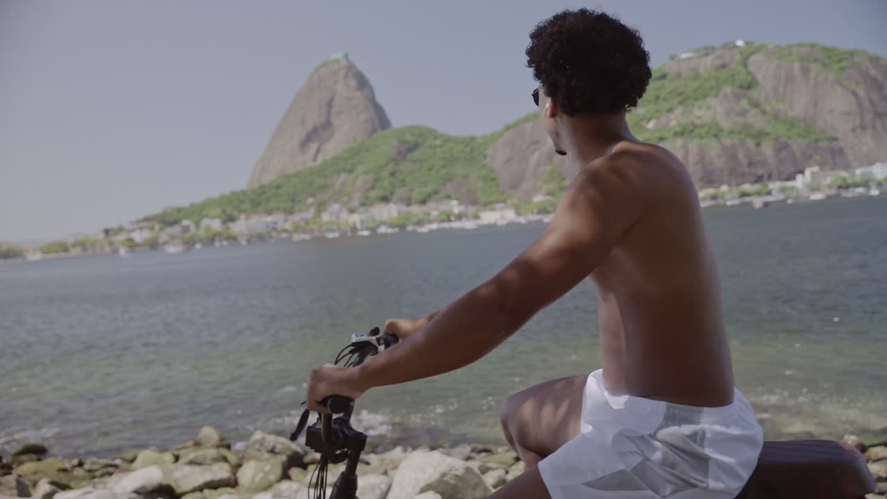 Man Cycling Along a Scenic Bay in Rio de Janeiro