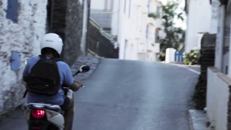 slow motion, man riding moped scooter down european street during summer