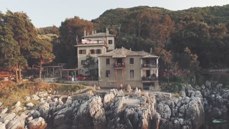 coastal house on a rocky shoreline with lush green hills