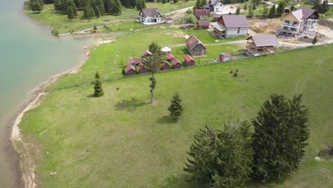 aerial take off shot of lake edge with ever green trees and building site