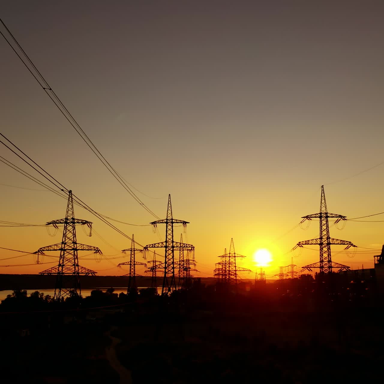 Dark electric towers against beautiful sunset. High-voltage electric lines in the evening on red and yellow sky.