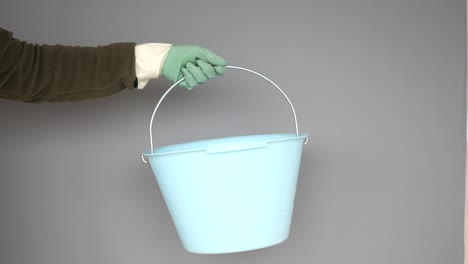 hand holding a light blue plastic bucket