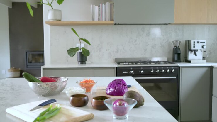 La telecamera sta riprendendo gli ingredienti mentre vengono posizionati uno a uno su un'isola da cucina in marmo per la preparazione dell'insalata